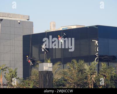 Kairo, Ägypten, 23. Januar 2024: Wartung und Reinigung des Außenbereichs eines Gebäudes, Glasreinigung durch Arbeiter an Drähten, um Reinigungsservice durch zu erbringen Stockfoto