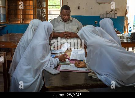 Muslimische Mädchen arbeiten mit ihrem Lehrer in einem Mathematikunterricht an der Jambiani Secondary School in Jambiani, Sansibar, Tansania. Stockfoto