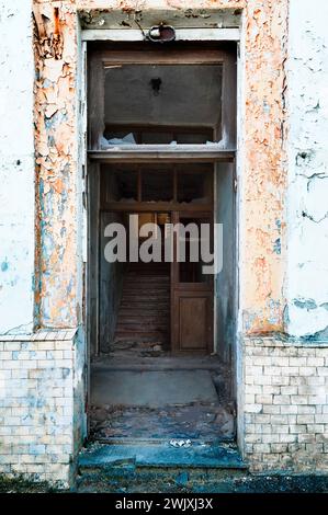 Verlassenes Haus in schlechtem Zustand. Risse in den Fenstern. Zerbröckelnde Wände und Holztüren. Urbane, verlassene Außenbezirke. Stockfoto