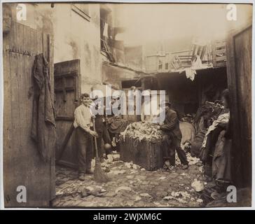 Porte d'Asnières, Cité Valmy, Ragpicker. Paris (XVII. Arr.). 1913. Fotografie von Eugène Atget (1857-1927). Paris, Carnavalet Museum. 53122-3 Annies Ten 1910 10, Besen, Kehren, Schikanen von Gütern, Slum, Ragpicker, Zitate valmy, Innenhof, gepflasterter Platz, im Fuß, Gruppe von Menschen, Mann, elend, Elend, sauber, Arm, Armut, Randlage, Menschen, Menschen, Menschen, Porte Asnieres, Gruppenporträt, städtisches Proletariat, Arbeit, altes Tuch, 20. XX. XX. 20. 20. 20. Jahrhundert, Haus Stockfoto