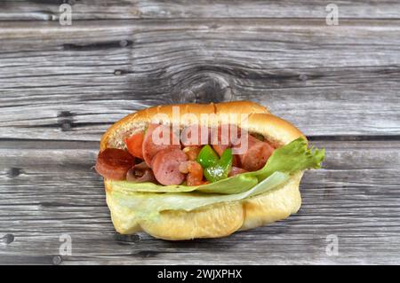 Teilweise geschnittenes Hotdog-Brötchen mit Scheiben von gegrilltem Rinderwurst, genannt wiener (Wiener Wurst) und frankfurter Frank, mit Tomatenscheiben, o Stockfoto