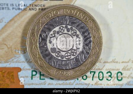 US-Dollar und zwei britische Pfund-Münze mit Königin Elizabeth II. Auf der Vorderseite und vier konzentrischen Kreisen für die Eisenzeit, Industrial Revo Stockfoto