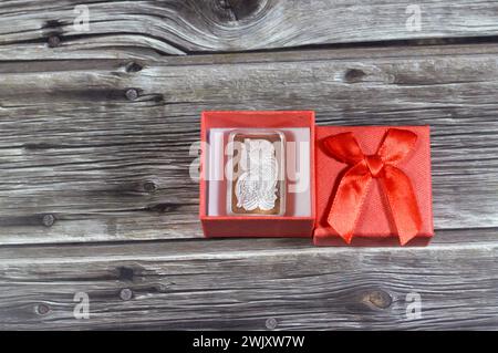 Eine rote Geschenkbox mit silbernem Edelmetallunzriegel aus reinem Silber. Der Preis für Silber wird durch Spekulation, Angebot und Nachfrage bestimmt und ist in der Regel b Stockfoto