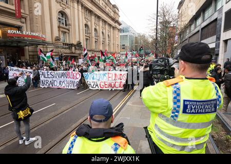 Manchester, Großbritannien. Februar 2024. Palästinensischer Gaza-Protest im Stadtzentrum von Manchester. Demonstranten marschierten durch das Stadtzentrum, überwacht von der Polizei. Die Demonstranten hielten an und hoben die Hände mit roten Handschuhen, um den Protest zu signalisieren, dass die Barclays Bank in Bezug auf den aktuellen Konflikt Blut an den Händen hatte. Der marsch hielt Straßenbahnen und Verkehr auf, während Tausende friedlich marschierten. Manchester UK. Quelle: GaryRobertsphotography/Alamy Live News Stockfoto