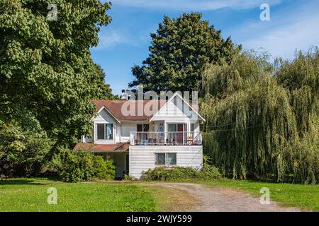 Einfamilienhaus auf Bauernhof gebaut. Wohnhaus mit großer grüner Rasenfläche vorne an sonnigem Tag in British Columbia. Typische Nordamerikanische Landwirtschaftsfarm Stockfoto