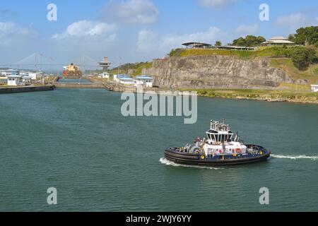 Colon, Panama - 23. Januar 2024: Schlepper vor den Schleusen der Agua Clara auf dem Panamakanal. Im Hintergrund auf einem Hügel befindet sich das Besucherzentrum Stockfoto