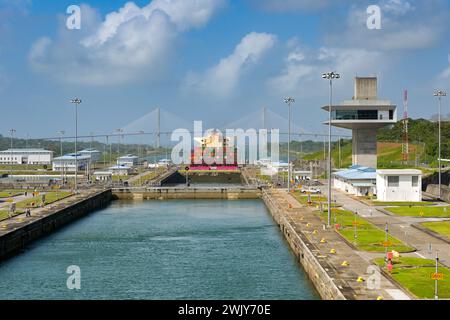 Colon, Panama - 23. Januar 2024: Schleusen und Kontrollturm von Agua Clara am Panamakanal. Im Hintergrund befindet sich ein Containerschiff und die Atlantikbrücke Stockfoto