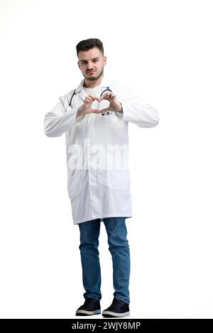 Doktor, in voller Länge, auf weißem Hintergrund, zeigt ein Herz Stockfoto