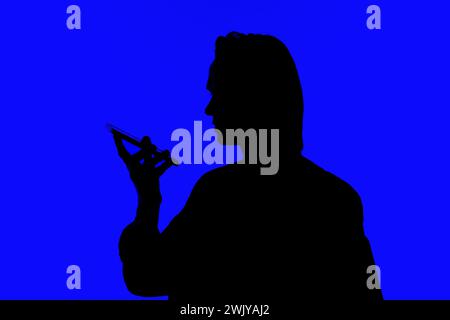 Silhouette ein eleganter Geschäftsmann, der auf einem Mobiltelefon spricht, in einer Jacke, die auf einem blau leuchtenden Hintergrund steht, futuristische KI-Konzepte Stockfoto