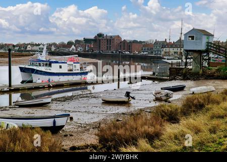 Wells-next-the-Sea, Norfolk, England, Großbritannien - Boote liegen am Steg und am Strand im Hafen bei Flut. Die blaue Hütte ist die Gezeitenrekorder Station Stockfoto