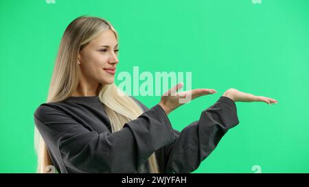 Eine Frau, Nahaufnahme, auf grünem Hintergrund, zeigt zur Seite Stockfoto