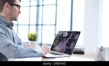 Ein männlicher Büroangestellter bei einem Online-Meeting mit Kollegen Stockfoto