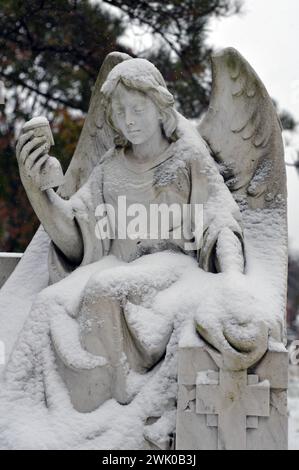 Schneebedeckte Skulptur eines Engels an einem Grab auf dem Montrealer Friedhof Notre-Dame-des-Neiges. Stockfoto