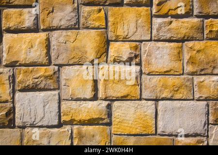 Nahaufnahme einer nuancierten gelb geschnittenen Steinmauer. Stockfoto