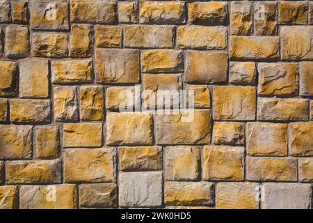 Nahaufnahme einer nuancierten gelb geschnittenen Steinmauer. Stockfoto