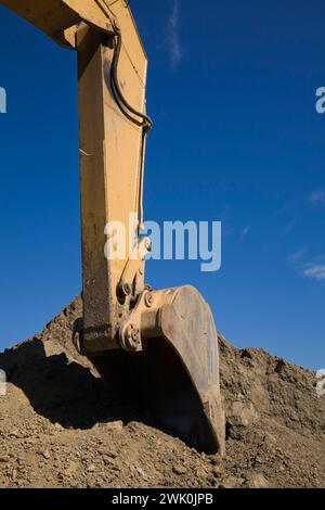 Nahaufnahme der mechanischen Schaufel am Baggerlader, der Boden aufnimmt. Stockfoto