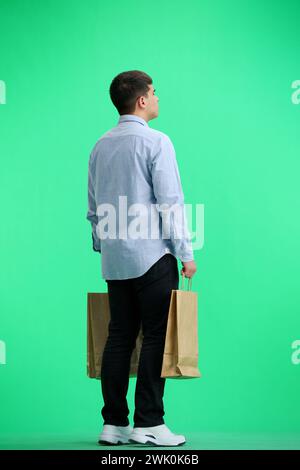 Ein Mann in voller Länge, auf grünem Hintergrund, mit Taschen Stockfoto