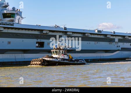 Schlepper 'SD Suzanne' eskortiert den Flugzeugträger 'HMS Prince of Wales', der Portsmouth Harbour, Portsmouth, Hampshire, an der Südküste Englands ablegt Stockfoto