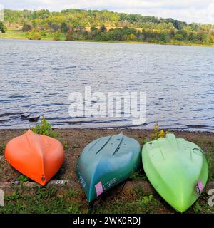 Die 3 Kanus haben verschiedene Farben und sitzen auf dem Land. Stockfoto