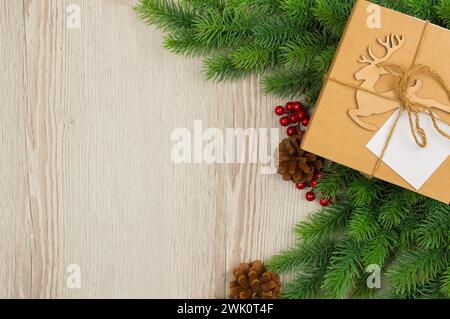 Neujahrsgeschenkkasten mit Hirsch, Zweig-weihnachtsbaum auf hölzernem Hintergrund. Banner mit Leerzeichen für Text. Rustikaler Hintergrund. Vintage-Holzbalken mit C Stockfoto