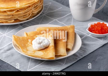 Pfannkuchen mit Sauerrahm und rotem Kaviar. Nahaufnahme von Pfannkuchen, die auf einem Teller gestapelt sind Stockfoto