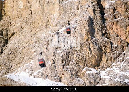 Fahrgastkabinen mit der Seilbahn, die an einem sonnigen Wintertag auf einem schneebedeckten Felsgipfel in den europäischen Alpen auf- und absteigen Stockfoto