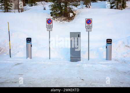 Ladestation für Elektrofahrzeuge auf einem schneebedeckten Parkplatz in einem Skigebiet in den Alpen im Winter Stockfoto