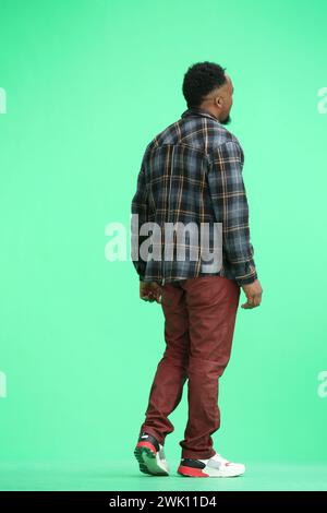 Ein Mann in voller Höhe, auf grünem Hintergrund, läuft Stockfoto