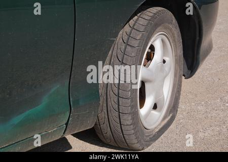 Nahaufnahme des Platten Reifens an der Vorderseite des grünen Autos. Stockfoto