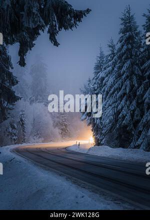 Ein Auto, das im Winter auf einer verschneiten Straße fährt Stockfoto