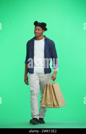 Ein Mann in voller Länge, auf grünem Hintergrund, mit Taschen Stockfoto
