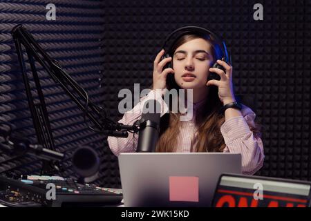 Fokussierte Audioingenieurin, die Kopfhörer in Studio anpasst Stockfoto