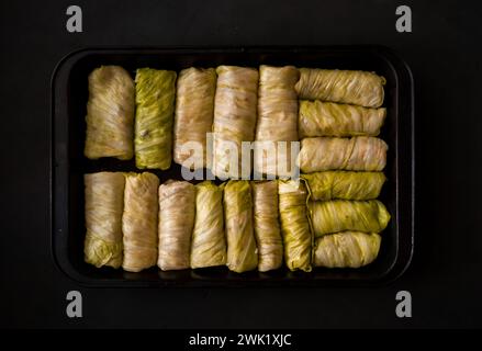 Gefüllte Kohlrollen in einem Backblech auf schwarzem Hintergrund. Selektiver Fokus. Getönt. Ukrainisches traditionelles Gericht. Osteuropäische Küche. Draufsicht Stockfoto