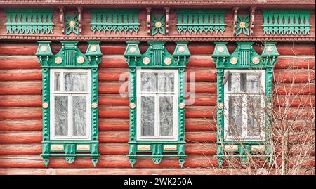 Drei Fenster mit geschnitzten Holzverzierungen und Architekraven an der Fassade des Blockhauses aus dem 19. Jahrhundert. Region Nischni Nowgorod, Russland. Architektonische Tiefen Stockfoto