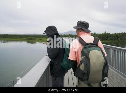 Touristen auf der Brücke über den Brooks River, beobachten Lachse, die unter der Brücke schwimmen. Katmai Nationalpark. Alaska. Stockfoto