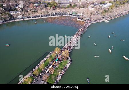 HANGZHOU, CHINA - 17. FEBRUAR 2024 - Kreuzfahrtschiffe fahren unter der kaputten Westseebrücke, die von Touristen stark besucht wird, in der Stadt Hangzhou, Zhe Stockfoto