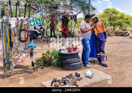 afrikanischer Unternehmer, Straßenverkäufer mit Kunde am Telefon, Verkauf von Werkzeugen, Wagenheber, Reifen, Kabeln, Elektrowerkzeuge und verschiedene Hardware Stockfoto