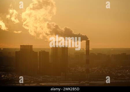 Dampfrohr über den Häusern einer Winterstadt mit Gebäuden im Schnee, Zeitraffer Stockfoto