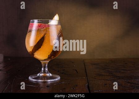 Glas mit einem Getränk auf braunem Hintergrund. Glas mit Obstscheiben. Trinken Sie auf dem Tisch. Kopierbereich. Stockfoto