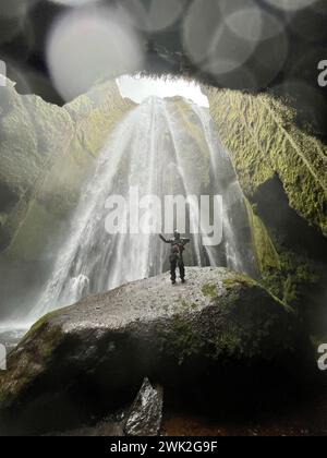 Mann unter einem Wasserfall in Island Stockfoto