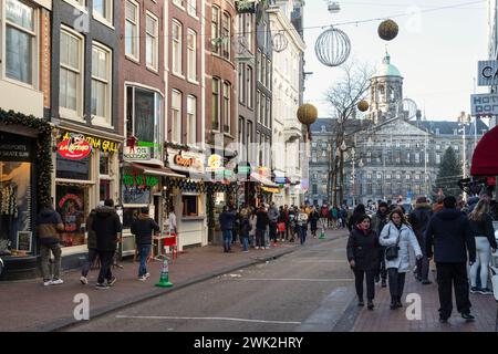 Geschäftige Einkaufsstraße in Amsterdam mit dem Königspalast auf dem Dam-Platz im Hintergrund. Stockfoto
