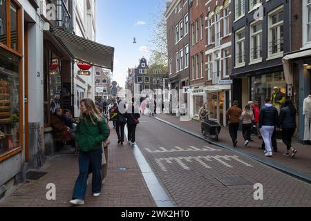Einwohner und Touristen schlendern durch die engen Einkaufsstraßen im Zentrum von Amsterdam. Stockfoto