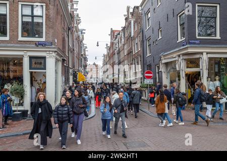 Einwohner und Touristen schlendern durch die engen Einkaufsstraßen im Zentrum von Amsterdam. Stockfoto