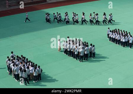 In einer Mittelschule in Shanghai leitet ein Lehrer eine Klasse von Schülern, um die Eröffnungszeremonie auf dem Spielplatz zu Proben Stockfoto