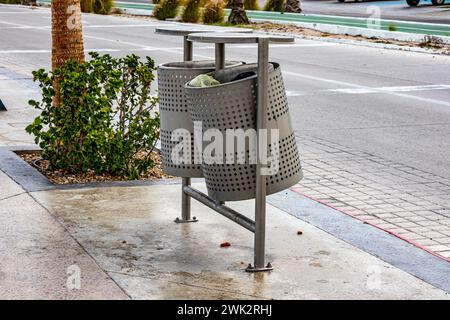 Zwei städtische Mülltonnen aus Metall mit Müll an der Touristenpromenade der Stadt, neben der Fahrzeugstraße im Hintergrund, bewölkter Tag in La Paz, Baja California Sur Stockfoto