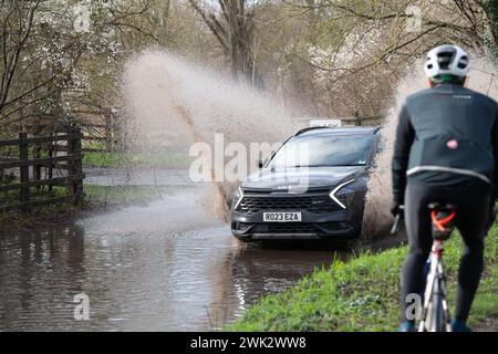 Eton, Windsor, Großbritannien. Februar 2024. Ein Autofahrer fährt nach starkem nächtlichem Regen mit hoher Geschwindigkeit durch Fluten, die Passanten in einem Land in Eton, Windsor, Berkshire vorbeispritzen. Quelle: Maureen McLean/Alamy Live News Stockfoto