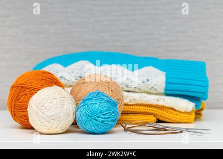 Warme Strickkleidung liegt auf einem Stapel. Strickpullover mit Wollfäden. Strickkleidung aus Wollfäden. Stockfoto
