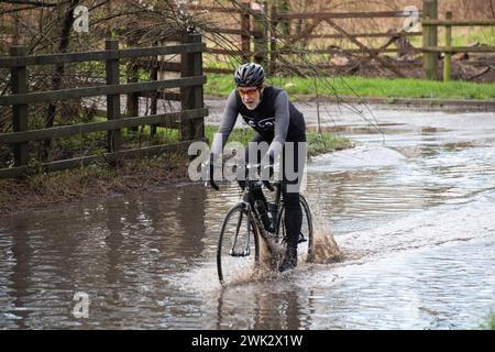 Eton, Windsor, Großbritannien. Februar 2024. Ein Radfahrer reitet durch Hochwasser in einem Land in Eton, Windsor, Berkshire, nach starkem nächtlichem Regen. Quelle: Maureen McLean/Alamy Live News Stockfoto