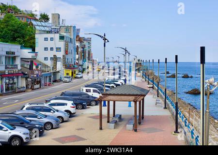 Donghae-Stadt, Südkorea - 28. Juli 2019: Die Küstenstraße am nördlichen Ende des Mukho-Hafens strotzt vor Aktivität, mit Autos, die entlang des Ro geparkt werden Stockfoto