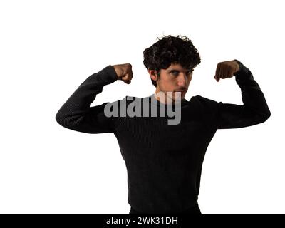 Ein Mann, der einen schwarzen Pullover und eine Hose trägt, wird gezeigt, wie er seine Muskeln in einer selbstbewussten Haltung beugt. Der Kontrast der schwarzen Kleidung zu seiner straffen Körperform verstärkt die visuelle Wirkung des Bildes. Stockfoto